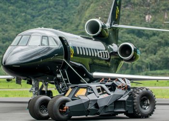 A black private jet is parked on a runway with a black, futuristic, armored car from Neymar Jr's collection in front of it
