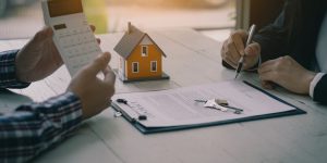 Real estate professionals offer their clients contracts to discuss home purchases, insurance or real estate loans. Home sales agents sit at the office with new home buyers in the office.
