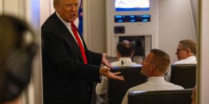 US President Donald Trump speaks to members of the press aboard Air Force One