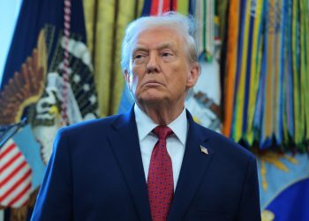 Donald Trump, standing in the Oval Office, frowns and looks to the side.