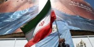 Homem-segura-bandeira-iraniana-perto-de-outdoor-anti-EUA-representando-o-presidente-dos-EUA-Donald-Trump-e-o-Estreito-de-Ormuz-em-Teera-Ira-em-30-de-maio-de-2026-e1781283180554