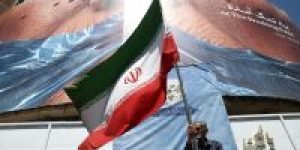 Homem-segura-bandeira-iraniana-perto-de-outdoor-anti-EUA-representando-o-presidente-dos-EUA-Donald-Trump-e-o-Estreito-de-Ormuz-em-Teera-Ira-em-30-de-maio-de-2026-e1782525884154
