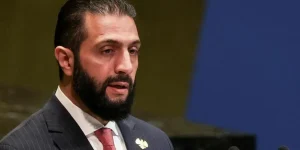Reuters Al-Sharaa speaks at the UN wearing a pinstripe suit and red tie.