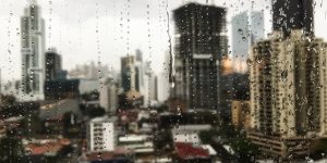 Beautiful view of the raindrops rolling down the window and the skyscrapers in the background