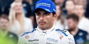 Carlos Sainz looks on during a Williams end-of-season photocall with faces of team staff in the background