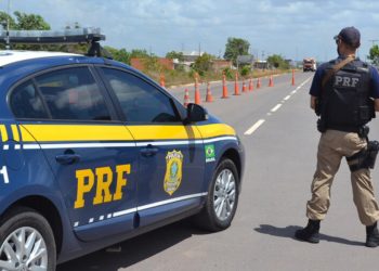 colorida de agente da PRF ao lado de viatura
