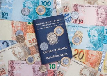 colorida de notas de dinheiro Real e moedas, além de uma Carteira de Trabalho