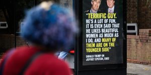 People read a poster about US President Donald Trump's relationship with dead sex trafficker Jeffrey Epstein