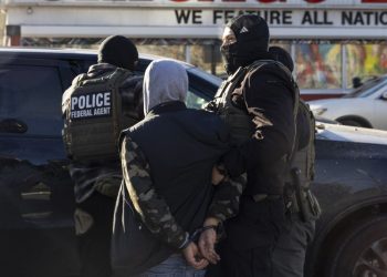 A federal agent arrests a man after stopping and questioning him in the street during an Immigration Enforcement Operation in Minneapolis on January 14, 2026