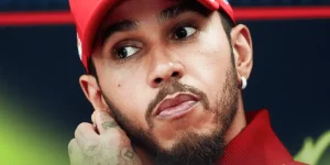 A close-up shot of Lewis Hamilton touching his ear in a press conference