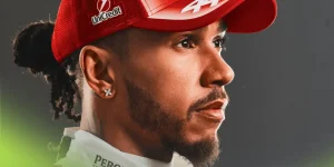 A portrait shot of Lewis Hamilton modelling Ferrari's 2026 cap and overalls