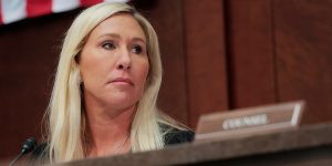 Rep. Marjorie Taylor Greene looking on.