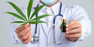 medical doctor holding cannabis leaf and bottle of cannabis oil