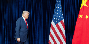 of Donald Trump walking on stage towards American and Chinese flags
