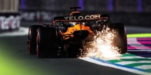 A rear-facing shot of Oscar Piastri's McLaren kicking up a shower of sparks over a kerb in Jeddah
