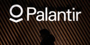 Illuminated Palantir logo on a wood-paneled wall.