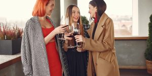 Happy women friends drinking red wine laughing in teracce